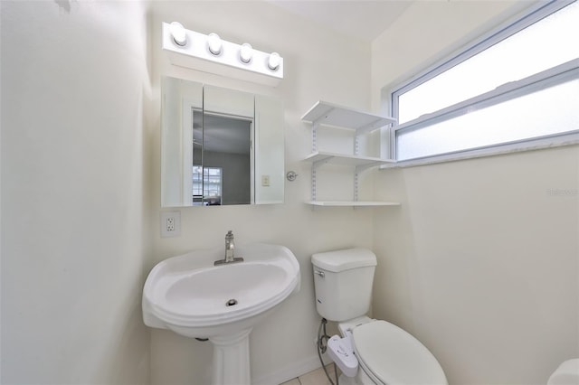 half bathroom with tile patterned floors, toilet, and a sink
