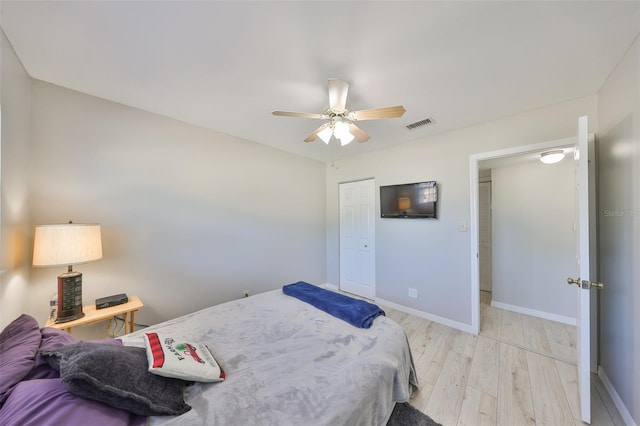 bedroom featuring light wood-style floors, a closet, ceiling fan, visible vents, and baseboards