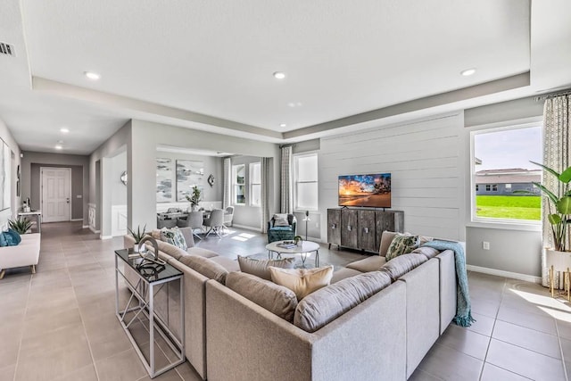 living room with a raised ceiling and light tile patterned flooring