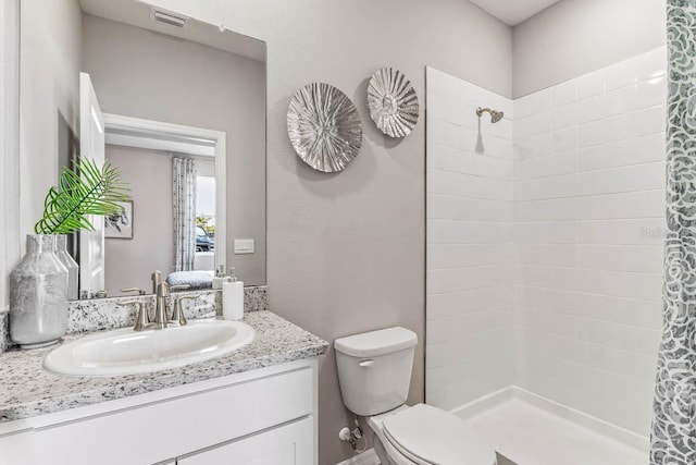 bathroom with walk in shower, vanity, and toilet