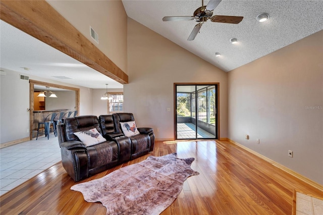 living room featuring a textured ceiling, a wealth of natural light, ceiling fan with notable chandelier, and light wood-type flooring