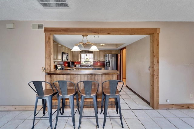 kitchen featuring stove, a kitchen breakfast bar, stainless steel refrigerator with ice dispenser, light tile patterned flooring, and kitchen peninsula