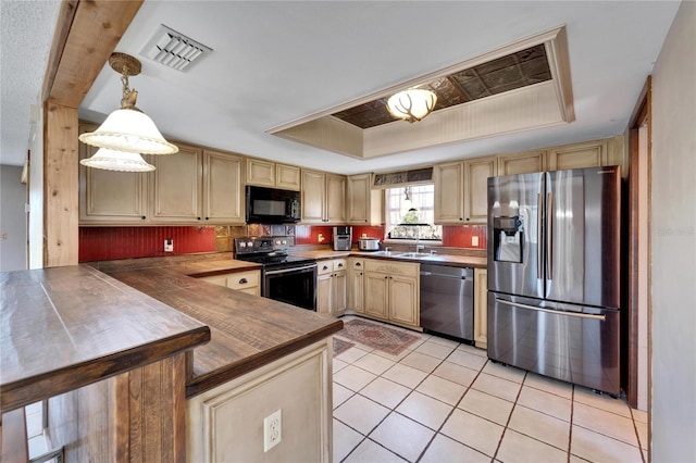 kitchen featuring wooden counters, a tray ceiling, black appliances, light tile patterned floors, and hanging light fixtures