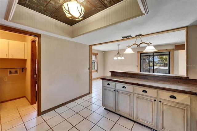 kitchen with a chandelier, pendant lighting, light tile patterned floors, and butcher block counters