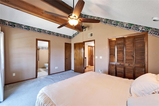 bedroom with connected bathroom, a textured ceiling, light colored carpet, ceiling fan, and vaulted ceiling with beams