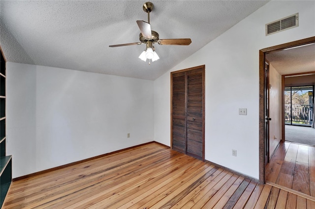 unfurnished bedroom with ceiling fan, a closet, light wood-type flooring, and vaulted ceiling