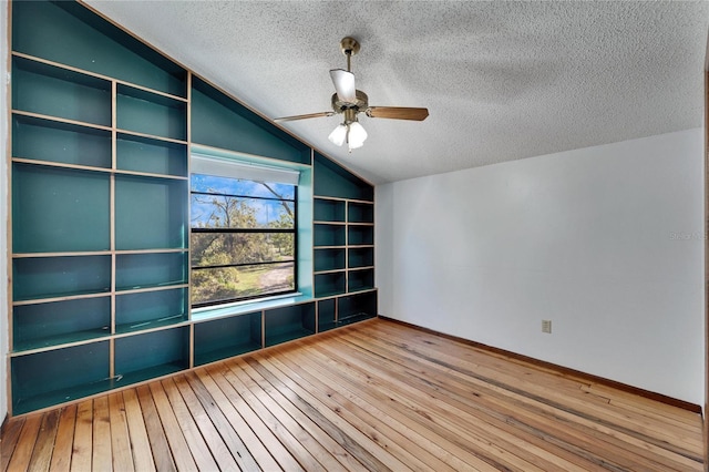 unfurnished room with hardwood / wood-style floors, a textured ceiling, vaulted ceiling, and ceiling fan