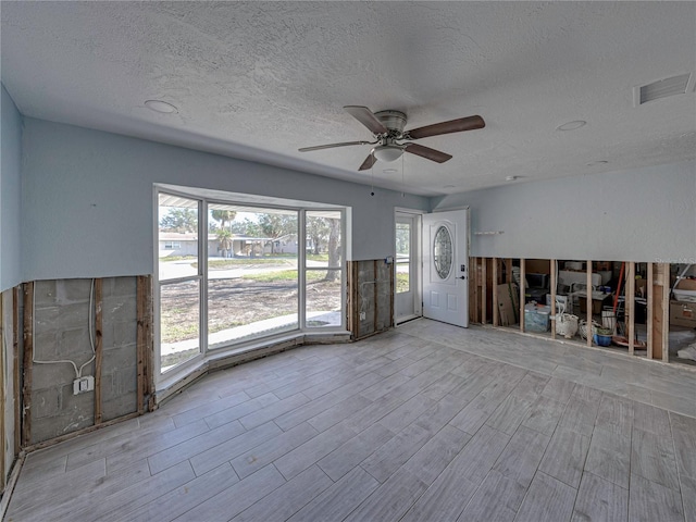 interior space with a wealth of natural light, ceiling fan, and a textured ceiling