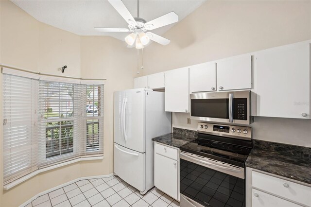 kitchen featuring appliances with stainless steel finishes, light tile patterned floors, white cabinetry, and dark stone countertops