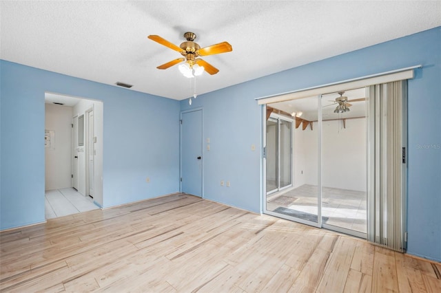 unfurnished room featuring ceiling fan, light hardwood / wood-style floors, and a textured ceiling