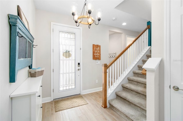 entryway with light wood-type flooring, a notable chandelier, and a wealth of natural light