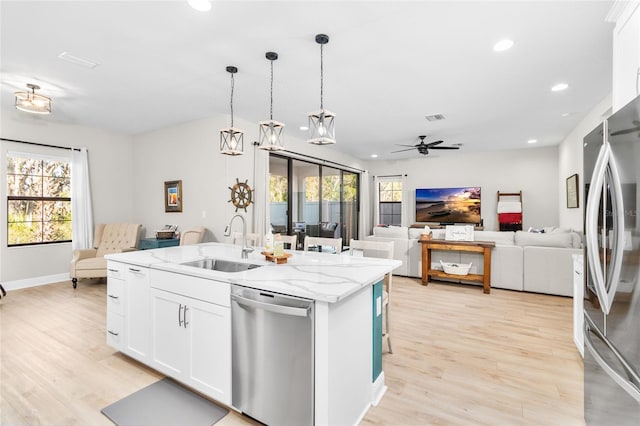 kitchen featuring white cabinets, sink, pendant lighting, stainless steel appliances, and a center island with sink