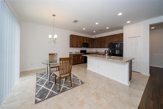 kitchen with a notable chandelier, a kitchen island with sink, black appliances, sink, and decorative light fixtures