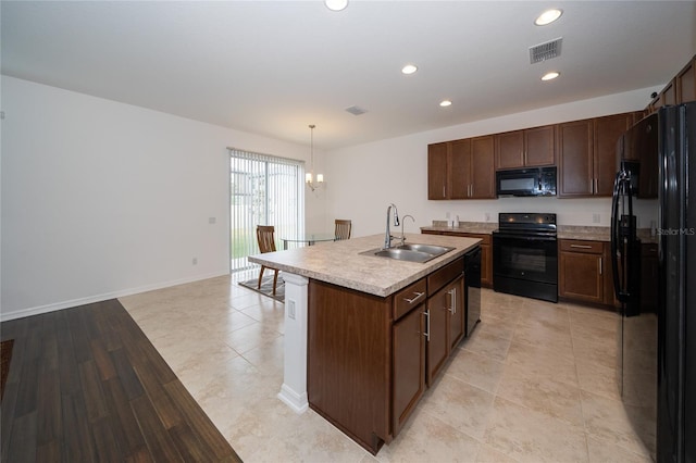 kitchen featuring a kitchen island with sink, sink, black appliances, pendant lighting, and a chandelier