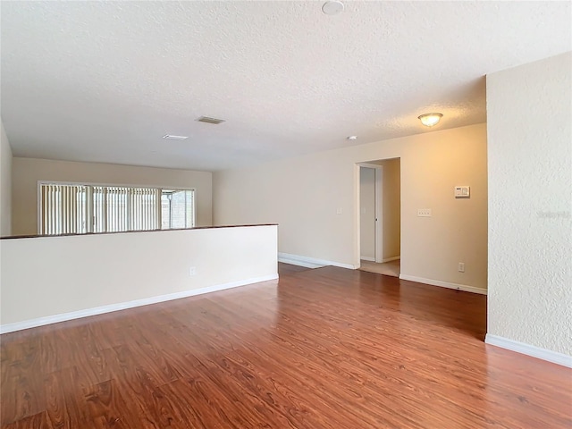 empty room featuring wood-type flooring and a textured ceiling