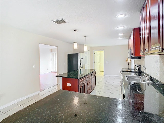 kitchen with pendant lighting, stove, dark stone counters, light tile patterned floors, and stainless steel fridge with ice dispenser