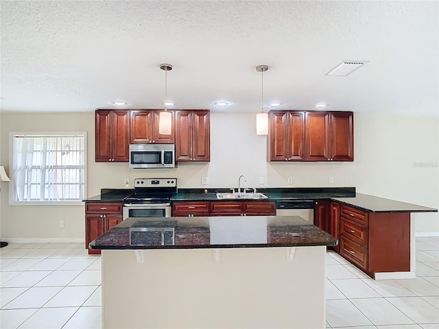 kitchen with a textured ceiling, decorative light fixtures, sink, and stainless steel appliances