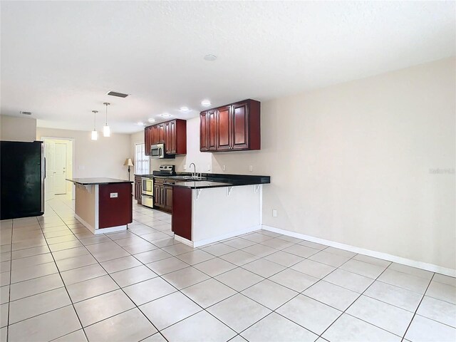 kitchen featuring a kitchen breakfast bar, hanging light fixtures, appliances with stainless steel finishes, light tile patterned flooring, and kitchen peninsula