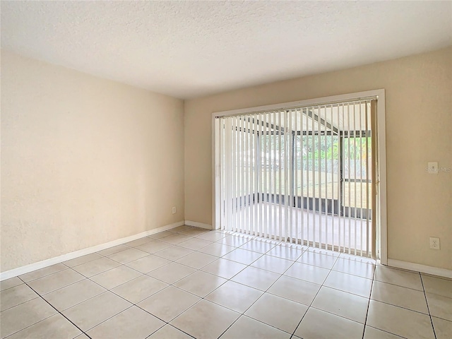 spare room with light tile patterned flooring and a textured ceiling