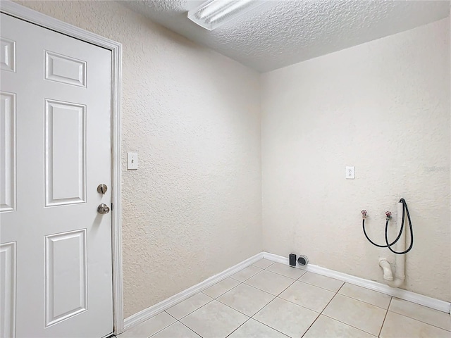 laundry area featuring light tile patterned floors, a textured ceiling, and hookup for a washing machine