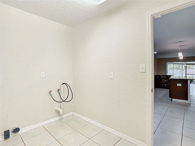 laundry room featuring hookup for a washing machine, a textured ceiling, and light tile patterned flooring