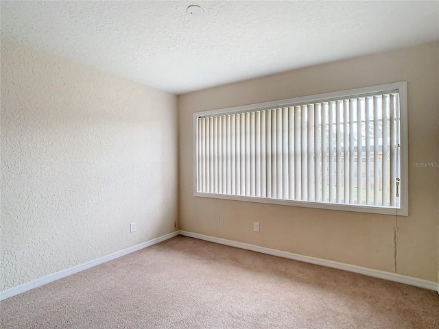 carpeted empty room with a textured ceiling