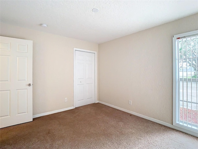 unfurnished bedroom with carpet floors, a textured ceiling, and a closet