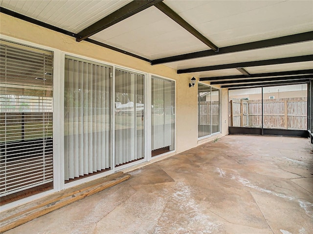 unfurnished sunroom featuring beamed ceiling