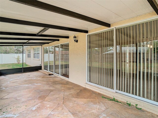 unfurnished sunroom featuring beamed ceiling