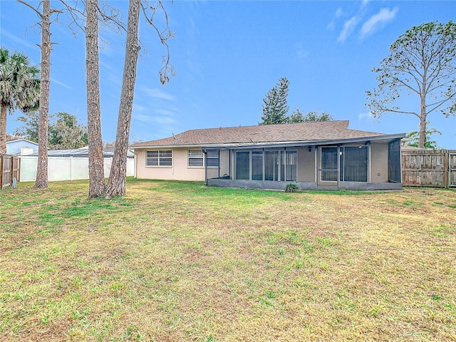 rear view of house with a lawn and a sunroom