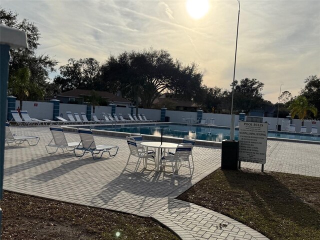 pool at dusk with a patio area