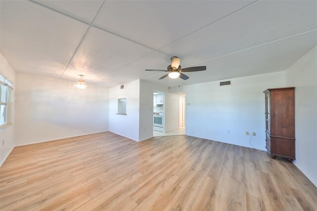 empty room featuring ceiling fan with notable chandelier and light hardwood / wood-style floors