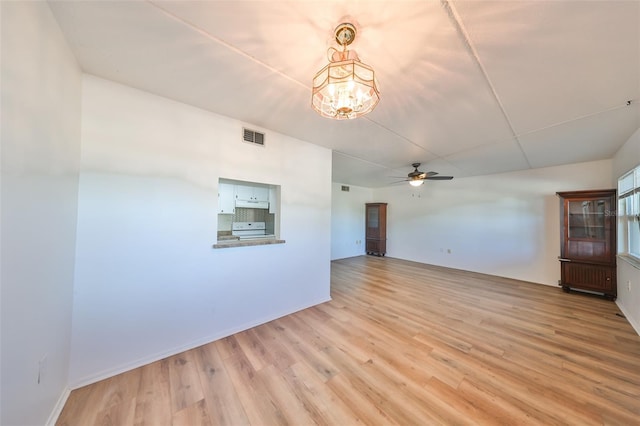 spare room featuring ceiling fan with notable chandelier and light wood-type flooring