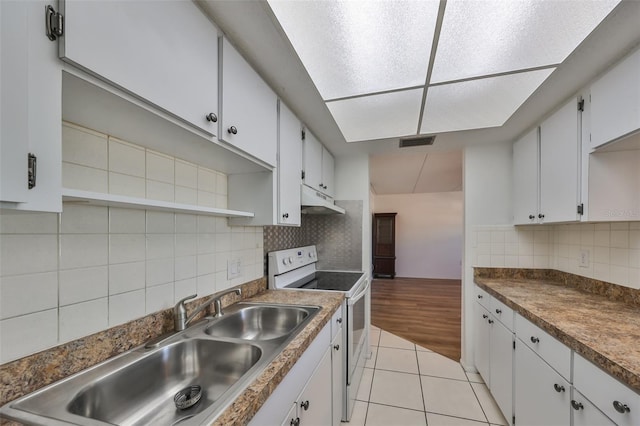 kitchen with backsplash, sink, electric stove, light tile patterned floors, and white cabinets