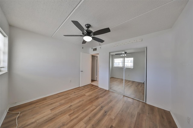 unfurnished bedroom featuring ceiling fan, wood-type flooring, a textured ceiling, and a closet