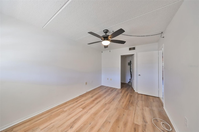 empty room featuring ceiling fan, light hardwood / wood-style flooring, and a textured ceiling