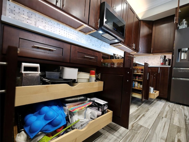 kitchen with light hardwood / wood-style floors, dark brown cabinetry, appliances with stainless steel finishes, and tasteful backsplash