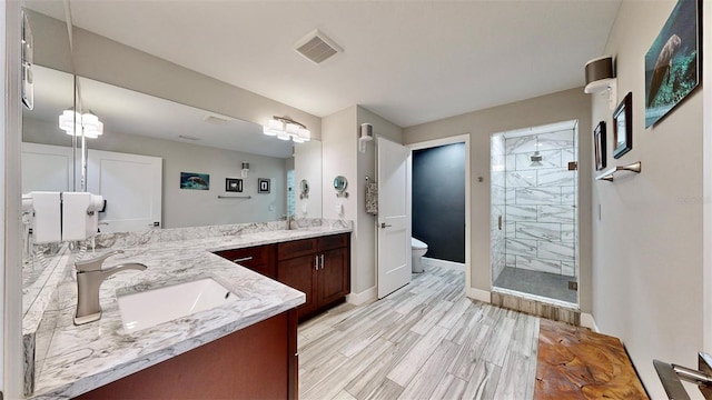 bathroom featuring hardwood / wood-style flooring, vanity, a shower with door, and toilet