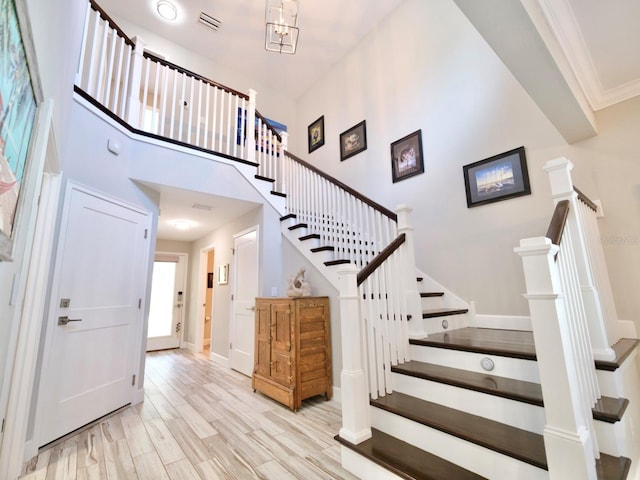 staircase with ornamental molding, a high ceiling, and wood-type flooring