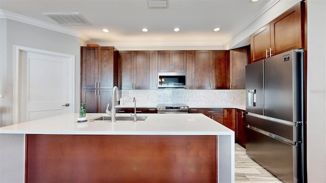 kitchen with stainless steel appliances, tasteful backsplash, a kitchen island with sink, and sink