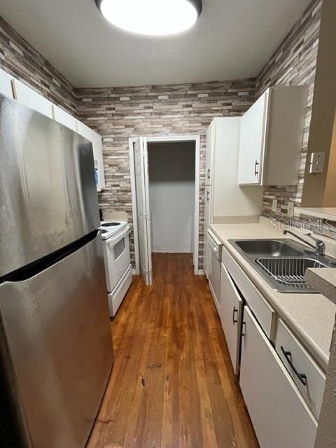 kitchen with sink, electric stove, white cabinets, dark hardwood / wood-style floors, and stainless steel refrigerator