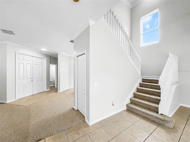 staircase with tile patterned floors and ornamental molding