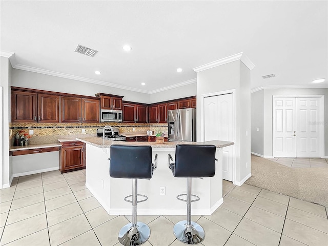 kitchen with a kitchen breakfast bar, a kitchen island with sink, light tile patterned floors, and stainless steel appliances