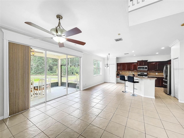 kitchen featuring a kitchen bar, tasteful backsplash, stainless steel appliances, ceiling fan, and a center island