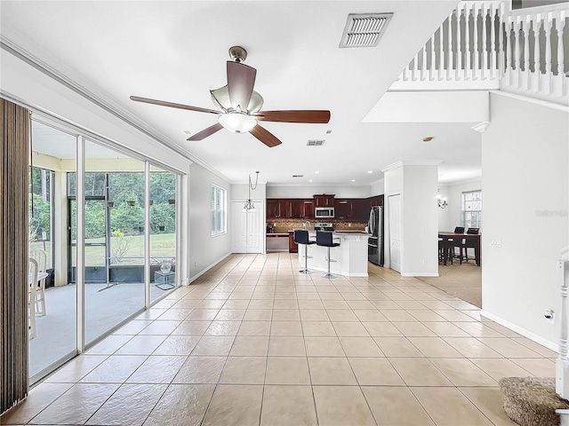 unfurnished living room with ceiling fan, light tile patterned flooring, and crown molding