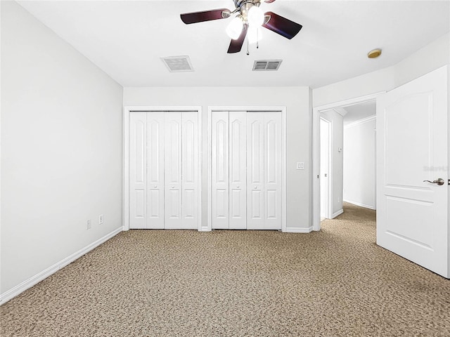 unfurnished bedroom with multiple closets and ceiling fan