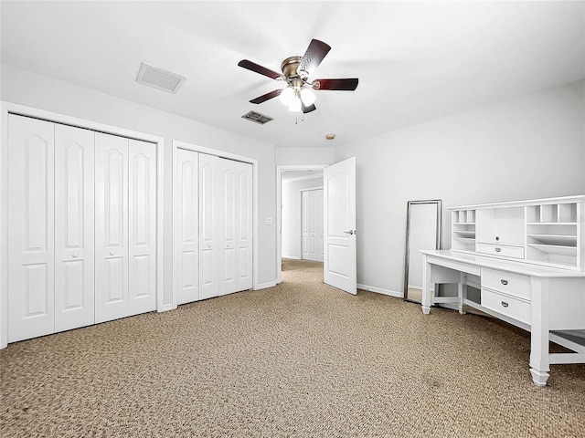 unfurnished bedroom featuring carpet floors, two closets, and ceiling fan