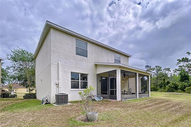 rear view of house with central AC, a lawn, and a sunroom