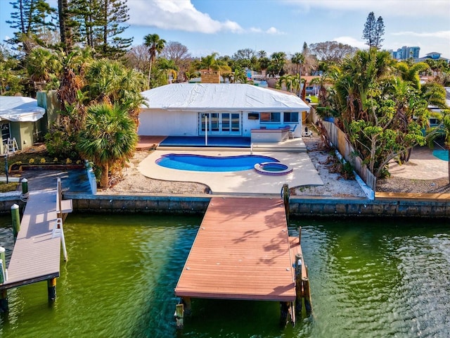 back of house with a swimming pool with hot tub, a water view, and a patio