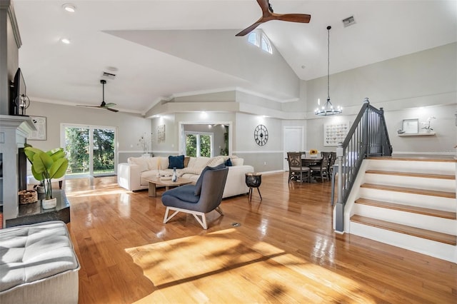 living room featuring ceiling fan with notable chandelier, wood-type flooring, and high vaulted ceiling